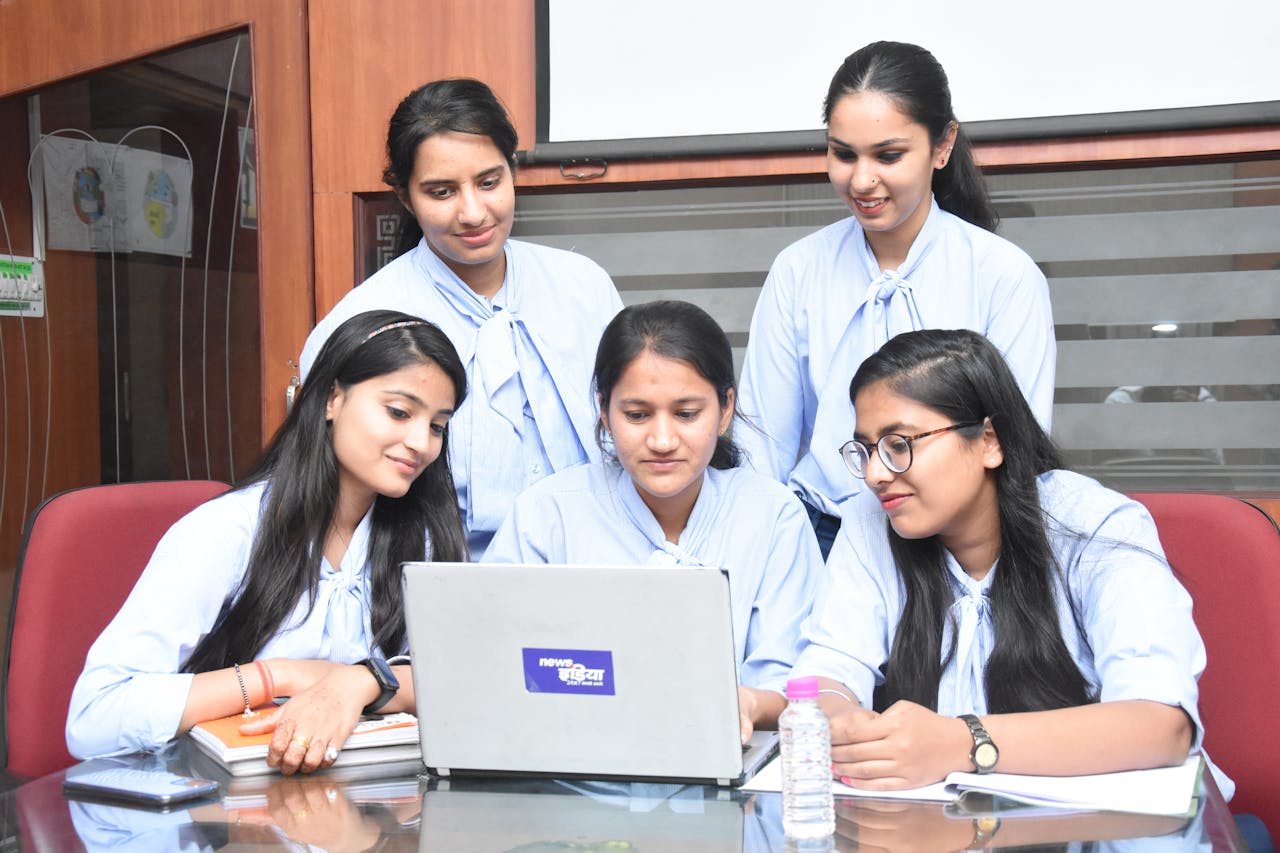 A group of young South Asian women working together on a laptop in a Jaipur office.