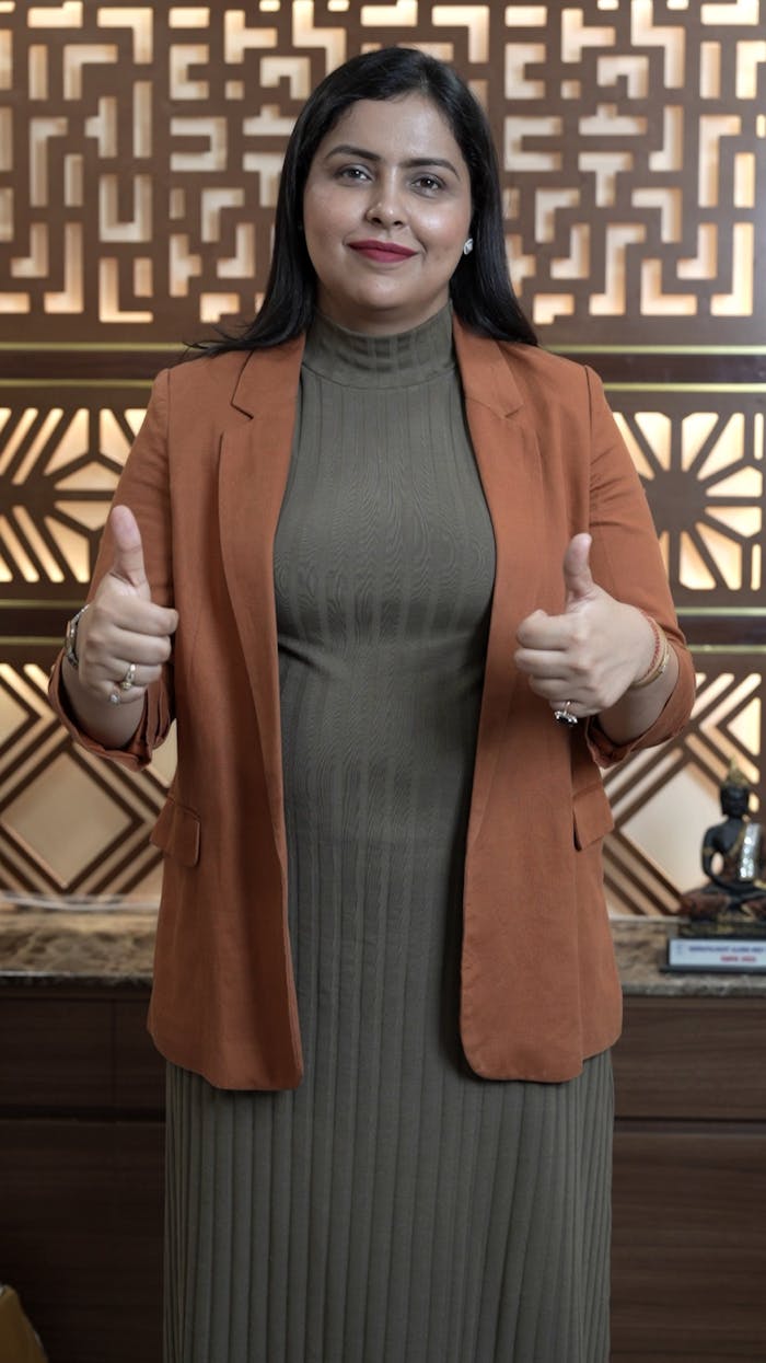 A professional woman in a stylish office setting giving a thumbs up, symbolizing success and confidence.