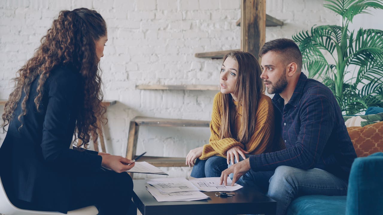 Young couple consulting with a business advisor in a modern office setting.