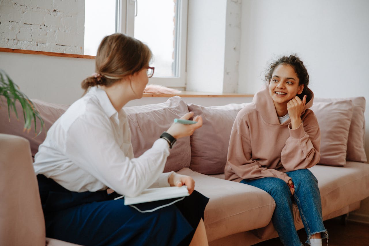 A therapist and young client engaging in a warm counseling session on a cozy sofa.